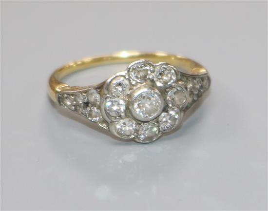 An early 20th century 18ct gold and nine stone diamond cluster ring with diamond set shoulders, size P.